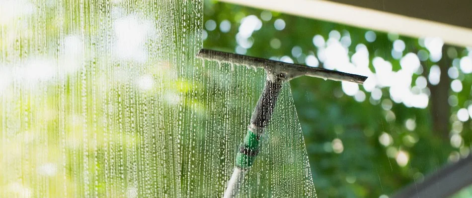 Cleaning a window in Lititz, PA, using a squeegee.